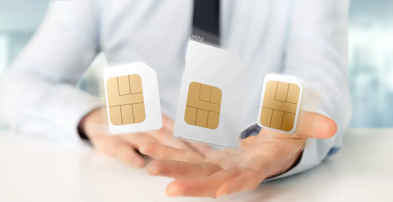 Main insérant une carte SIM M2M dans un traceur industriel fixé dans une camionnette de livraison.